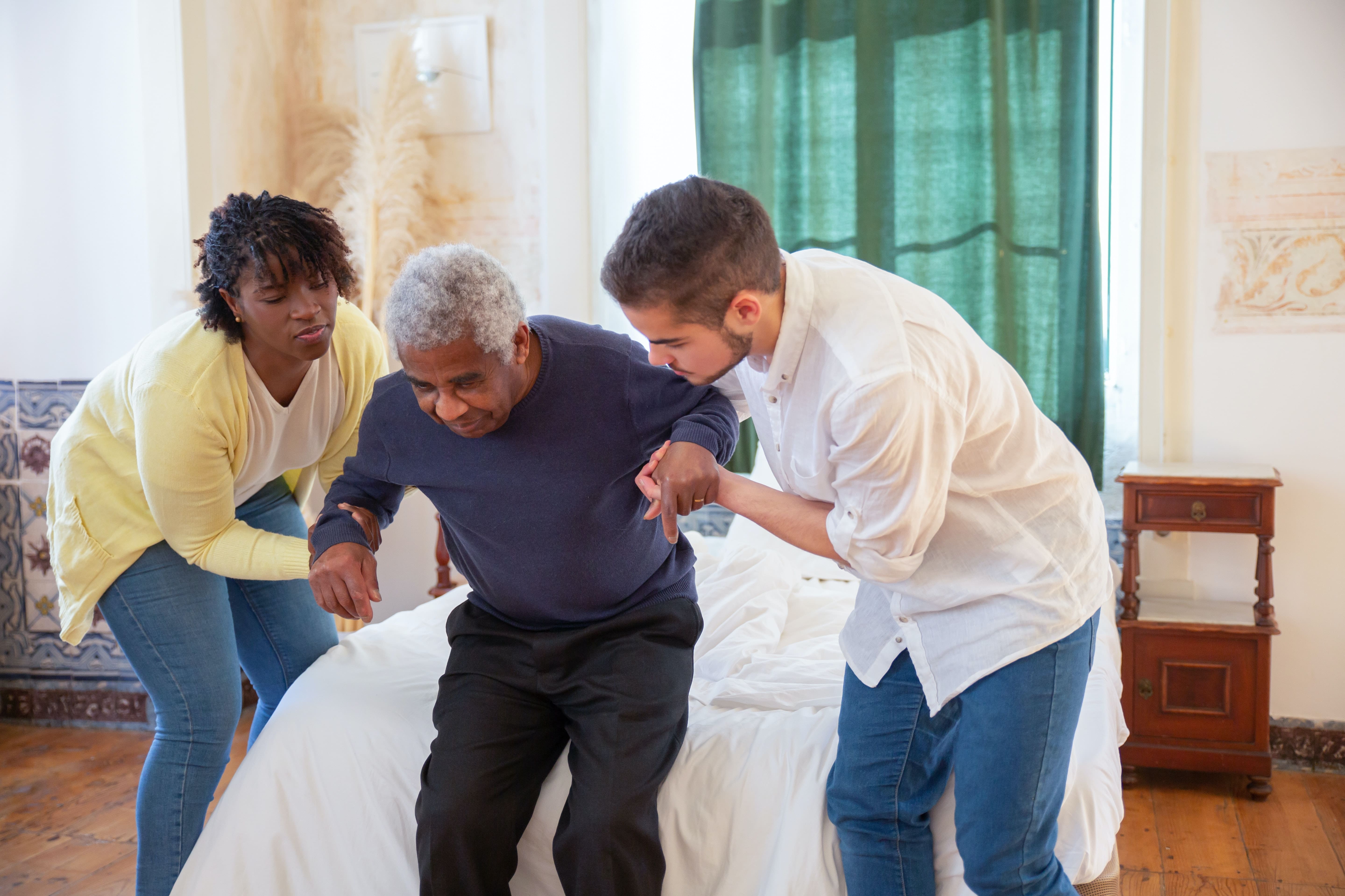 Nurses helping an elderly man get up